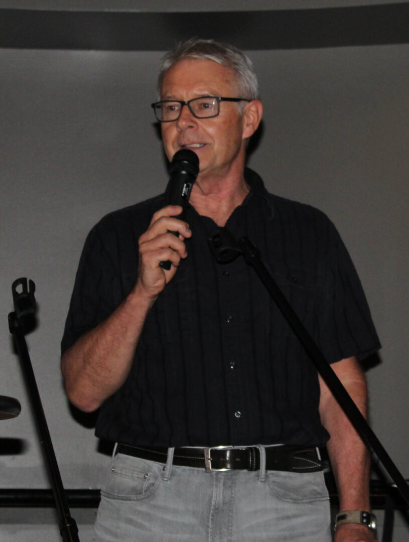 A man with glasses is holding a microphone