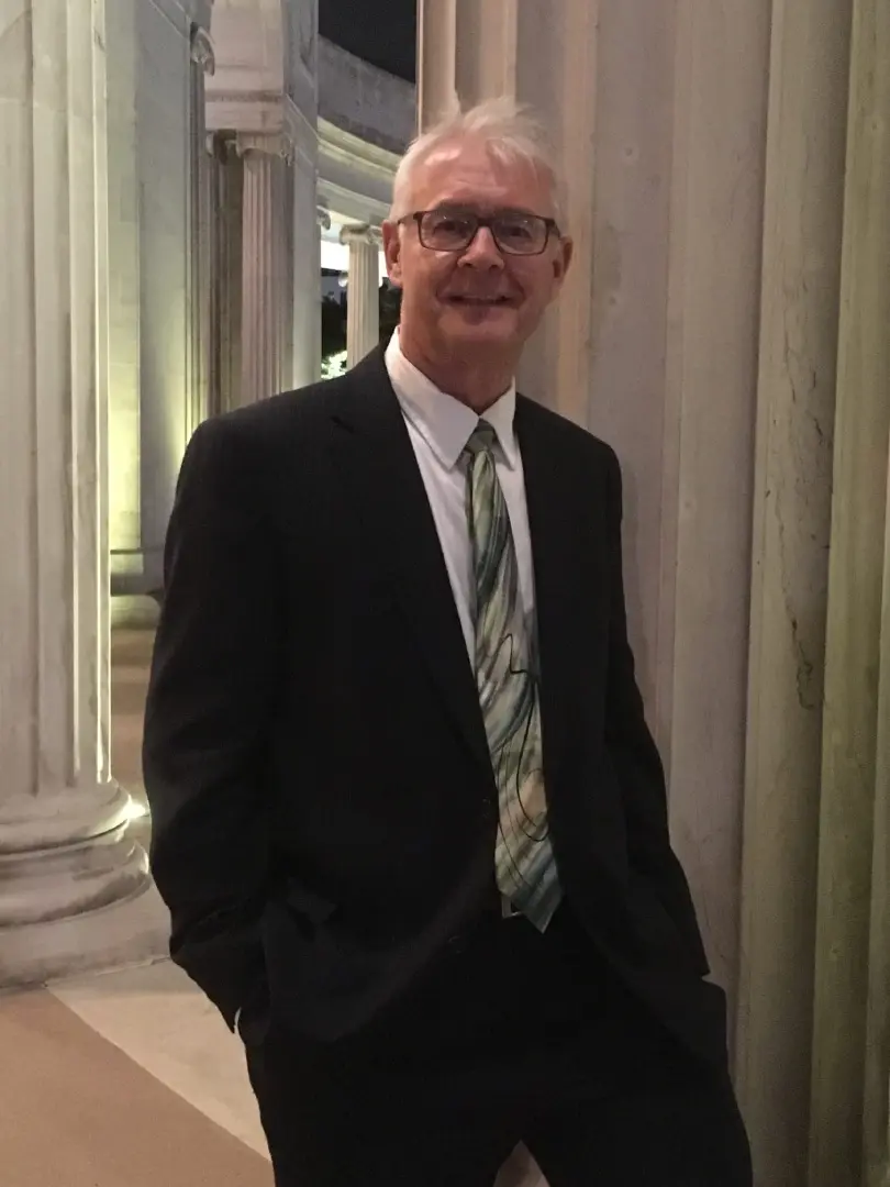 A man in suit and tie standing next to pillars.